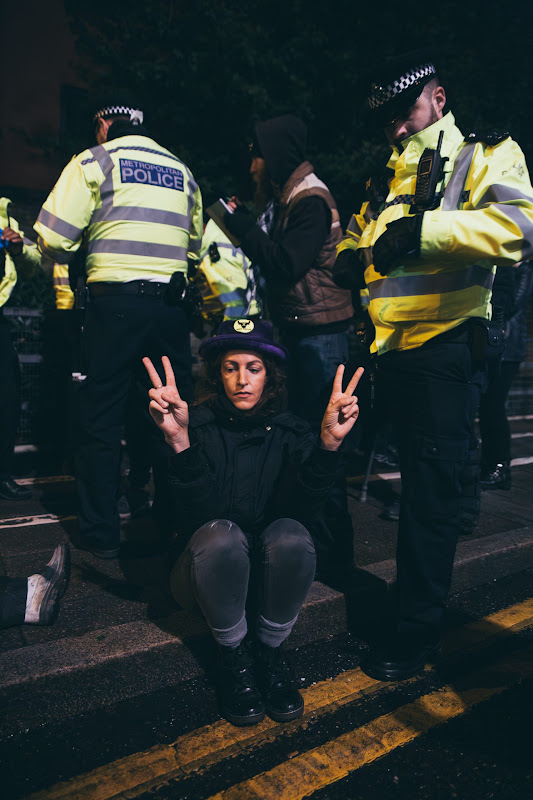Activist Holds Up Peace Signs Surrounded By Police At Fish Market Protest